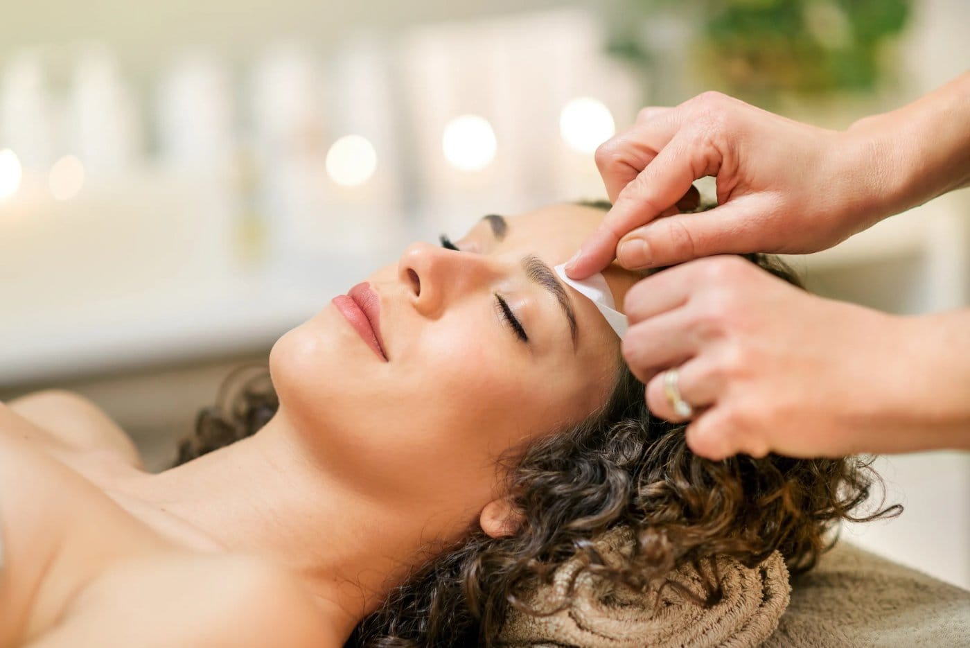 Gentle facial waxing, specialist removing brow hair with wax strips in a calm studio