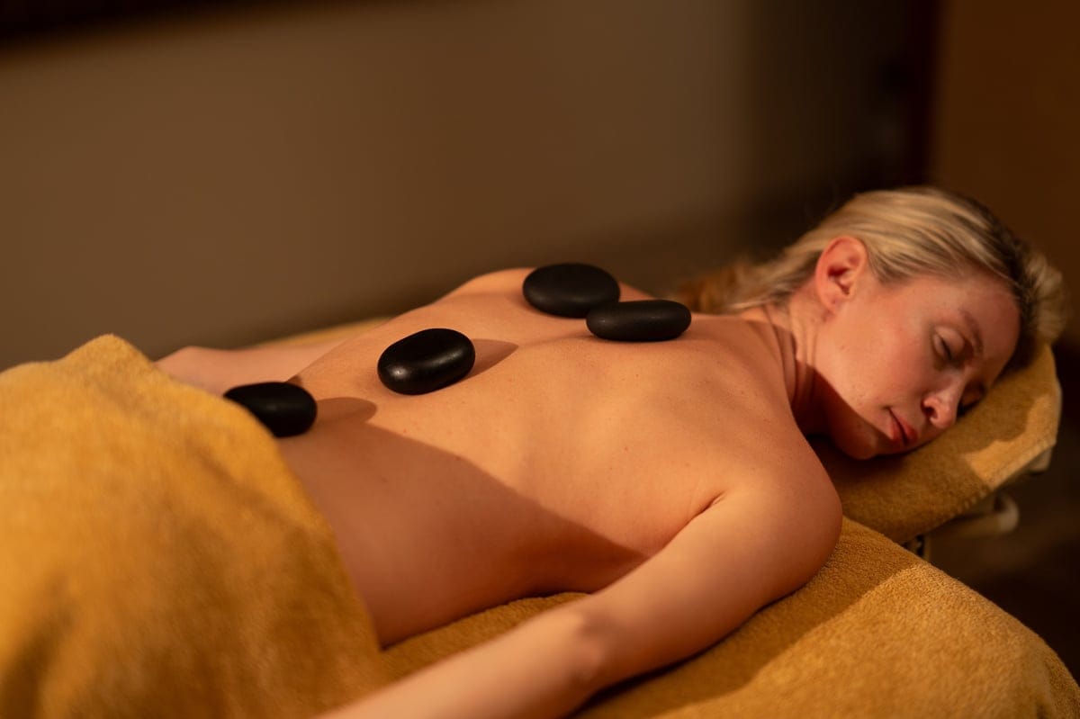 Guest relaxing during a hot stone massage session in a warm and calming spa room