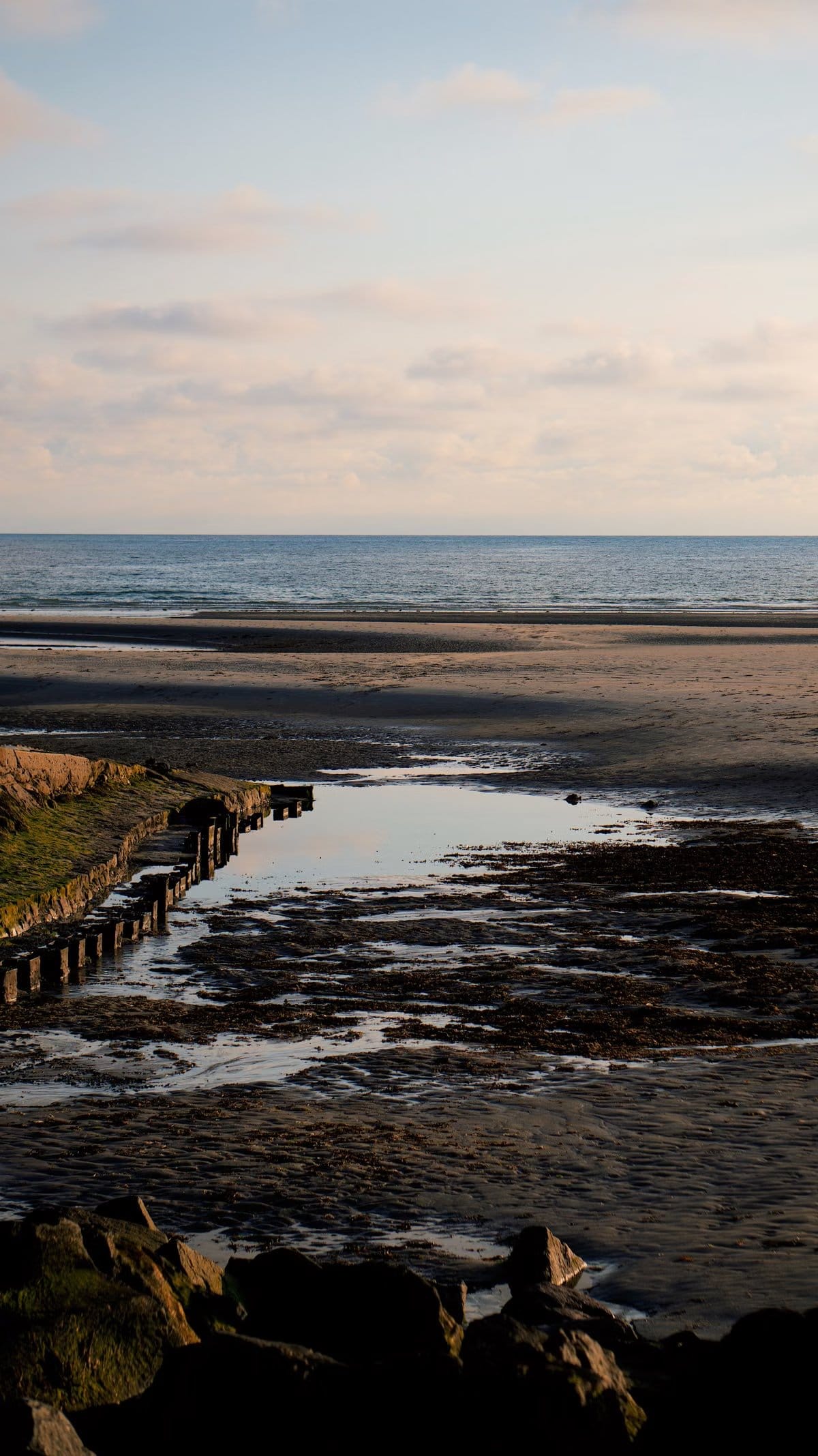 Serene sandy beach with calm ocean waves at sunset, like the wide beaches of Qualicum Beach